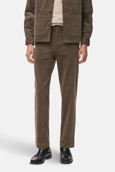 Pantalon marron de MANGO, en cuir de corduroy, associé à des loafers noirs en cuir et une veste coordonnée.