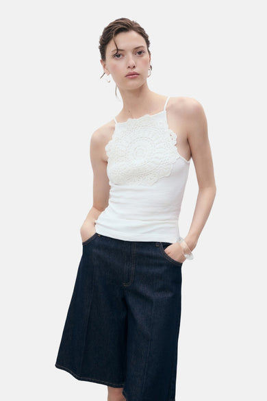 Witte top met spaghettibandjes van MANGO, met gehaakt detail op de borst en gecombineerd met denim culottes.
