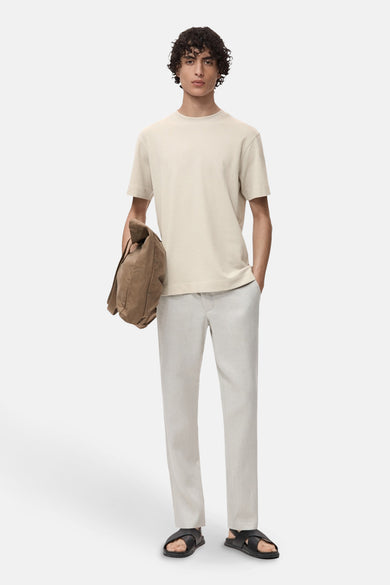 T-shirt gris à manches courtes de MANGO, porté avec un short léger et une sacoche marron.