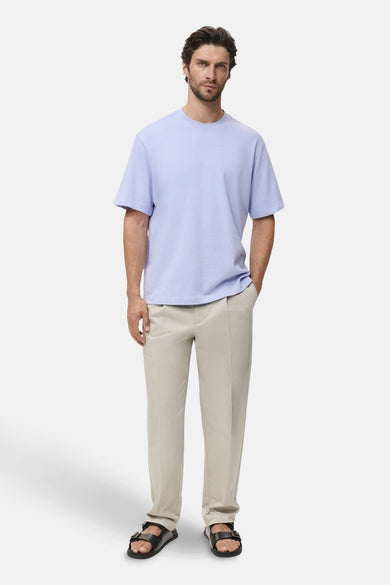 Blauw T-shirt met korte mouwen van MANGO, gedragen met een beige pantalon en zwarte sandalen.

