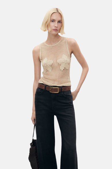 Beige tanktop van MANGO met bloemendetails, gecombineerd met een bruine riem en zwarte jeans.
