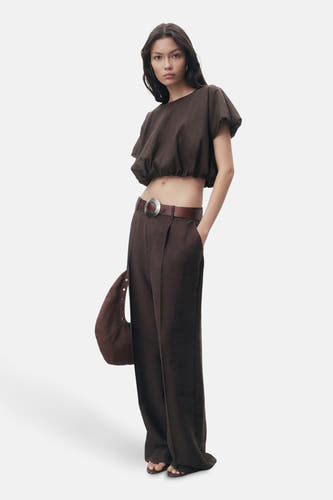 Bruine blouse met korte mouwen van MANGO, gedragen met een bruine broek met wijde pijpen en een riem.