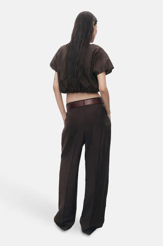 Bruine blouse met korte mouwen van MANGO, gezien van achteren, met donkere broek en riem.

