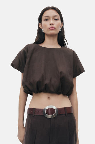 Bruine blouse met korte mouwen van MANGO, met een elastische zoom en gedragen met een bruine riem met zilveren gesp.
