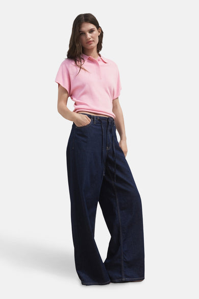 Roze polo met korte mouwen van MANGO, gedragen met wijde, donkerblauwe jeans met touwtjes.