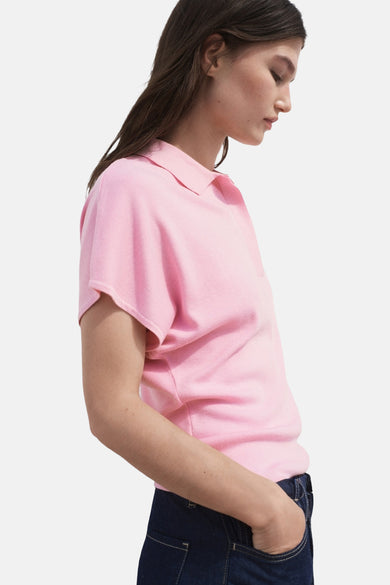 Roze polo met korte mouwen van MANGO, gedragen met een donkerblauwe jeans, zijaanzicht.
