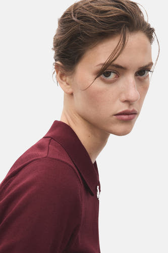 Bordeauxkleurige trui met ronde hals van MANGO, close-up van model met kapsel en rode kraag.