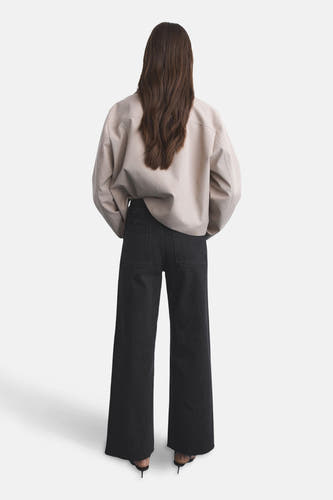 Jean wide de MANGO, avec des jambes larges et des poches arrière, associé à une veste beige et des baskets noires.