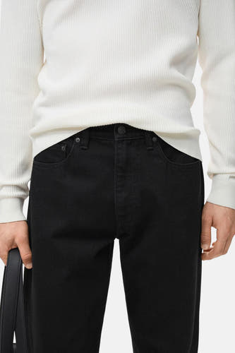 Jean droit noir de MANGO, avec une chemise blanche et un sac noir.