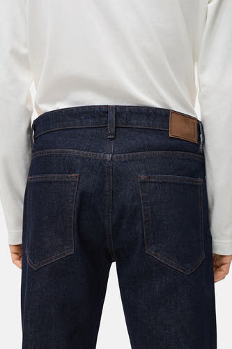 Donkerblauwe denim jeans van MANGO, achterkant gezien met bruin label en stiksels.