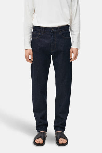 Donkerblauwe straight jeans van MANGO, met klassieke zakken en gedragen met een wit shirt en zwarte sandalen.
