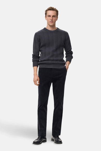 Grijze trui met ronde hals van MANGO, met een subtiel visgraatmotief en lange mouwen, gecombineerd met donkere corduroy broek en leren loafers.