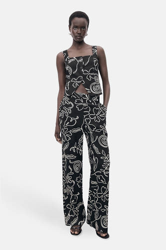 Pantalon noir avec imprimé MANGO, doté d'un motif de fleurs blanches et de vagues.