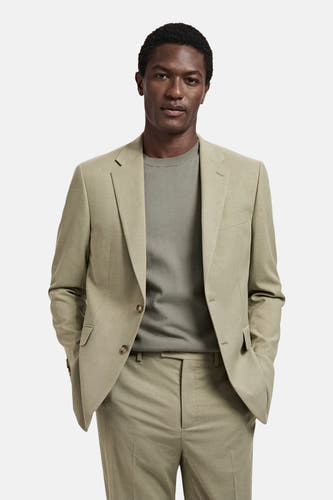 Blazer vert de MANGO, tailleur modèle avec collet revers et fermeture à boutons, combiné avec un pull et un pantalon verts.