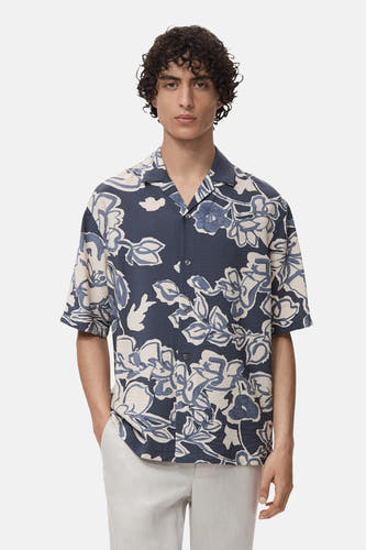 Chemise bleue à manches courtes de MANGO, avec un imprimé fleuri et portée avec une légère jupe.