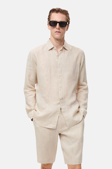 Beige linnen overhemd met lange mouwen van MANGO, gedragen met shorts en een zonnebril.