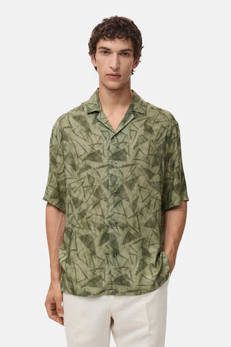 Chemise verte à manches courtes de MANGO, avec un motif triangulaire abstrait et une encolure ouverte.