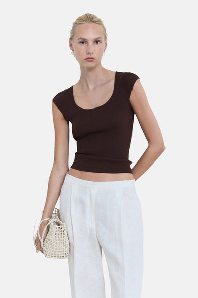 T-shirt sans manches MANGO de couleur marron, avec une texture rayée, associé à un pantalon de lin blanc et un sac tricoté.