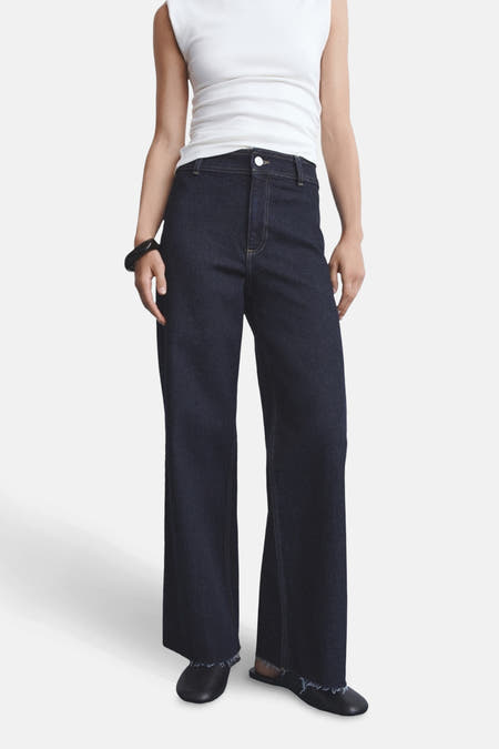 Jean bleu marine, large de MANGO, avec une droitte droite et des boutons à l'ourlet, associé à une chemise blanche.