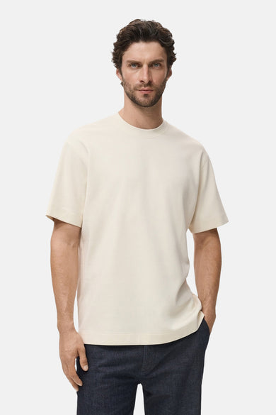 Beige T-shirt met korte mouwen van MANGO, gedragen met een donkere broek.