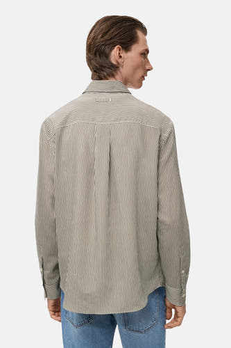 Kaki overhemd met lange mouwen van MANGO, met een streepjespatroon en plooi op de rug, gedragen met een jeans.
