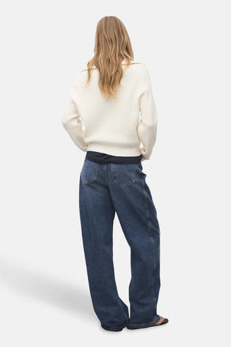 T-shirt à col rond blanc de MANGO, avec des manches longues, associé à des jeans larges et des sandales noires, vu de dos.