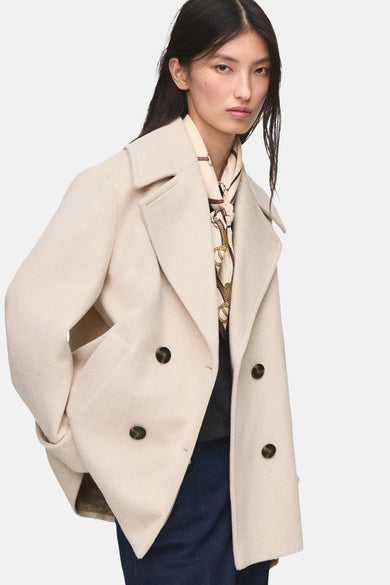 Beige korte jas van MANGO, met dubbele rij knopen en een sjaal met kettingmotief.