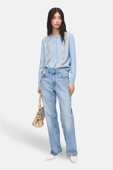 Blauw gilet van MANGO, met argyle patroon op de voorkant, gecombineerd met een wijde jeans en witte pumps.
