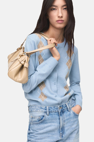 Blauw gilet van MANGO, met een argyle ruitpatroon, gedragen over een lichtblauwe spijkerbroek en met een beige handtas.
