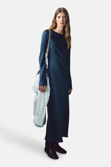 Robe bleue à manches courtes de MANGO, portée avec des chaussures noires et une veste blanche sur l'épaule.