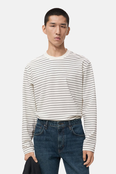 T-shirt blanc à manches longues de MANGO, avec un motif rayé horizontal et porté avec des jeans bleus foncés.