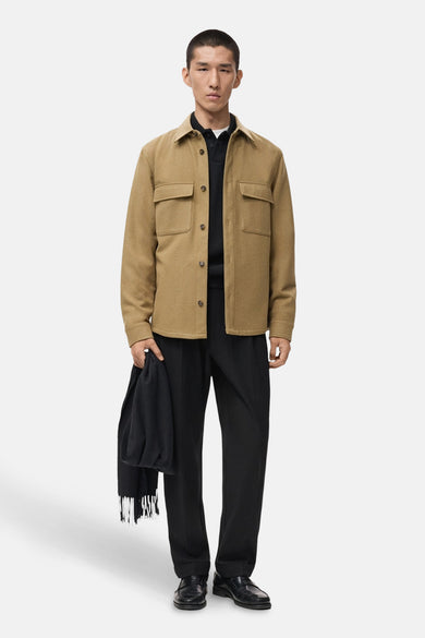 Manteau court brun de MANGO, avec des poches et une jupe noire et un foulard.