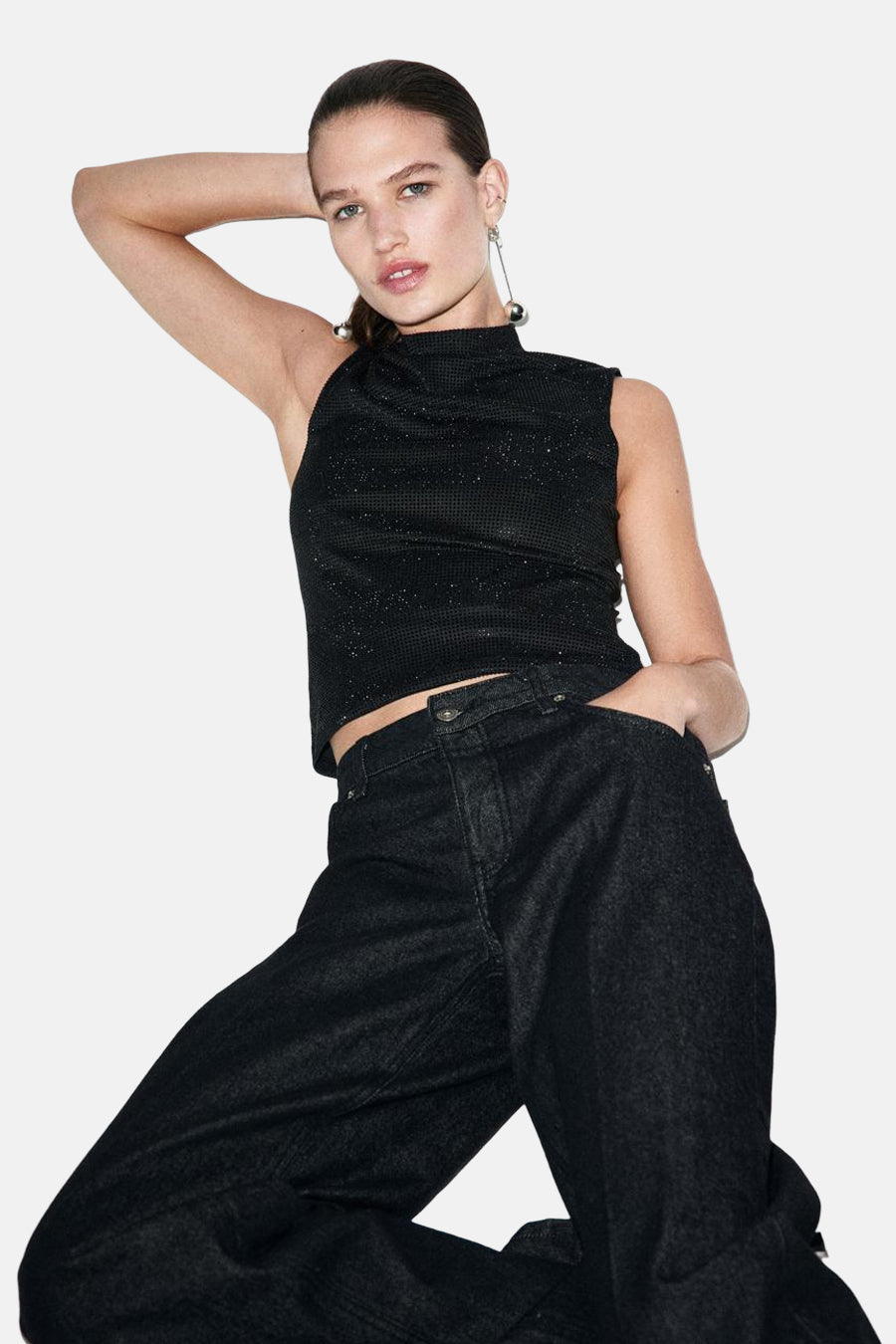 Blouse sans manches noire de MANGO, avec un subtil éclat et portée avec des jeans larges et sombres.