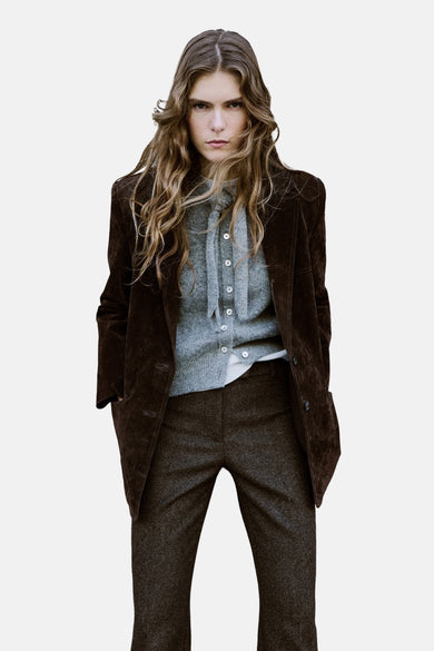 Grijs gilet van MANGO, gedragen over een wit shirt, met bruine blazer en pantalon.
