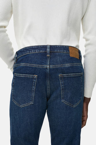 Jean tapered bleu marine de MANGO, vu de derrière avec un étiquette en cuir marron.