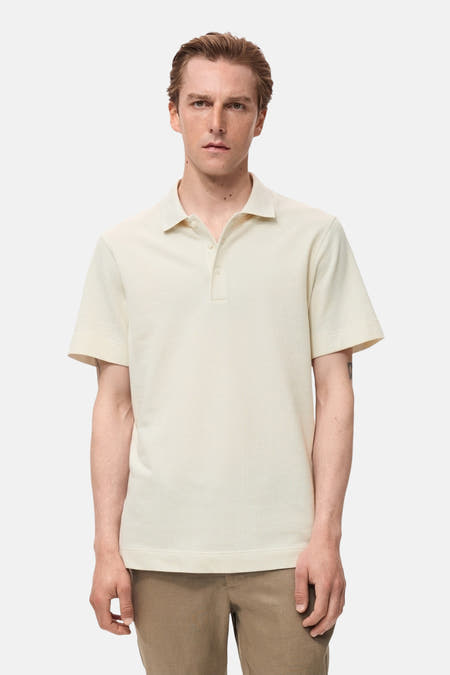 Ecru polo met korte mouwen van MANGO, met een subtiele textuur en gedragen met een kaki broek.
