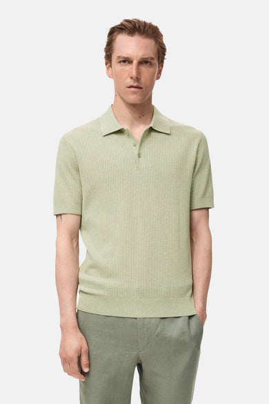 Groene polo met korte mouwen van MANGO, met fijne ribtextuur, gedragen met een groene broek.
