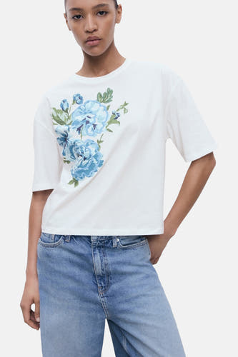 T-shirt multicolore à manches courtes de MANGO, avec une impression de fleurs bleues et porté avec un jean bleu.