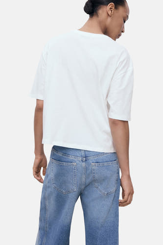 T-shirt blanc à manches courtes de MANGO, porté avec des jeans bleus, dos.