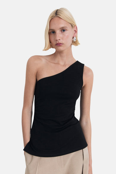 T-shirt sans manches noir de MANGO, avec une ligne d'épaules asymétrique, associé à un pantalon beige.