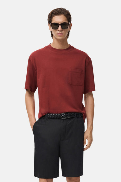 T-shirt rouge à manches courtes de MANGO, avec une poche poitrine, combinéé des shorts noirs et un ceinture tressée.