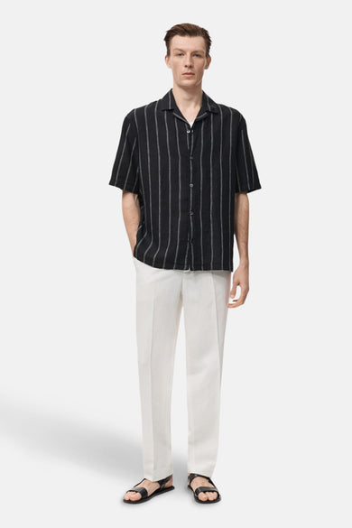 Zwart overhemd met korte mouwen van MANGO, met een gestreept patroon, gecombineerd met een witte broek en zwarte sandalen.