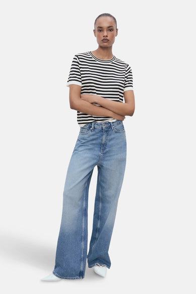 Multicolor T-shirt met korte mouwen van MANGO, met horizontale strepen, gecombineerd met wijde jeans en witte schoenen.