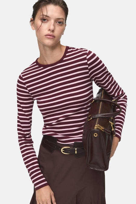 Bordeaux T-shirt met lange mouwen van MANGO, met horizontale strepen en gecombineerd met een bruine rok met riem.

