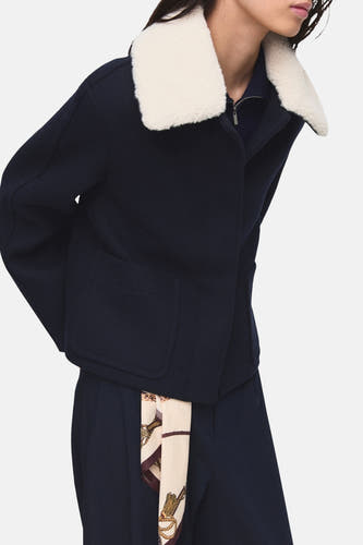 Blauwe korte jas van MANGO, met een witte kraag en een zijden sjaal als accessoire.
