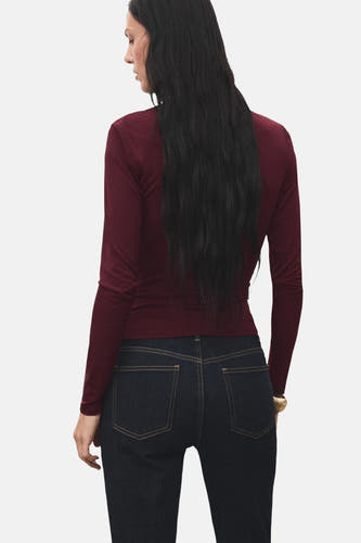 Bordeaux T-shirt met lange mouwen van MANGO, gezien van achteren, gecombineerd met donkere jeans.