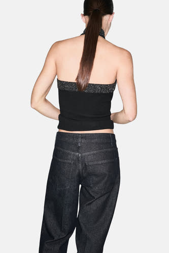 Zwarte mouwloze blouse van MANGO, met pailletten bovenrand, gecombineerd met donkere jeans en een paardenstaart.