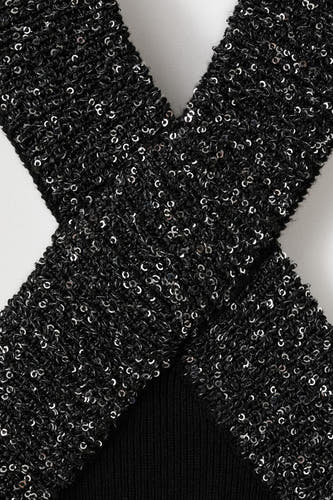 Mouwloze zwarte blouse van MANGO met een gekruist ontwerp en glanzende pailletten.
