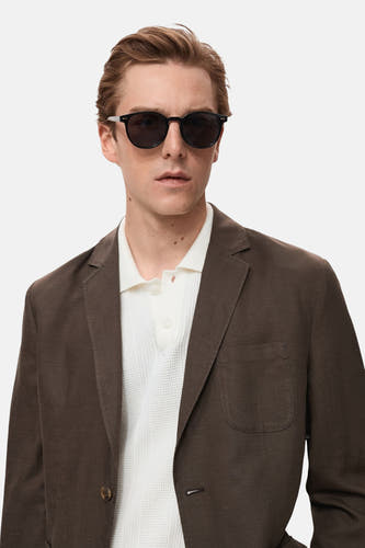 Bruine blazer van MANGO, met reverskraag en een enkele knoopsluiting, gedragen over een wit poloshirt.
