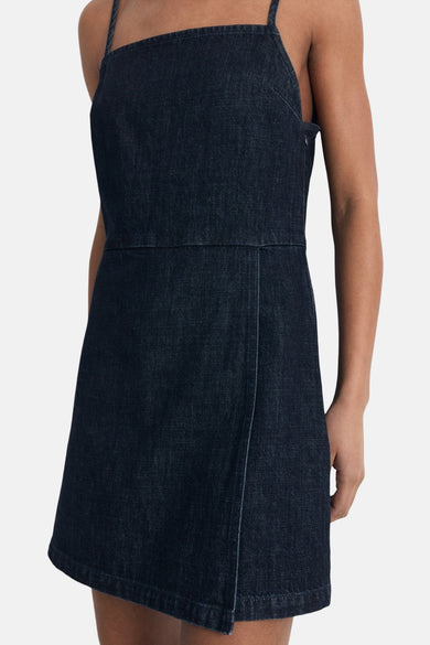 Combinaison en denim bleu marine de MANGO, avec un détail wrap-over et des bretelles spaghetti.
